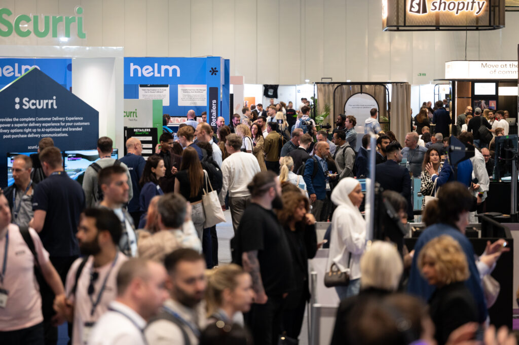 A busy UK exhibition hall filled with professional trade show stands and visitors networking.