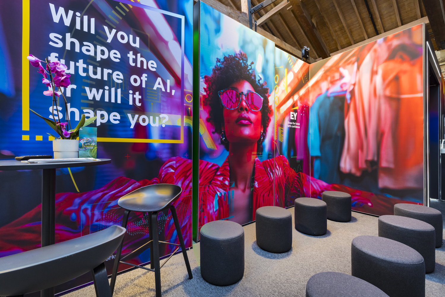 Colourful branded exhibition stand featuring a striking digital display, ambient lighting, and lounge-style seating designed to encourage visitors to dwell.