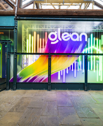 Backlit LED display at an exhibition stand entrance showing colourful branded graphics, demonstrating how LED screens can anchor a stand's visual identity.